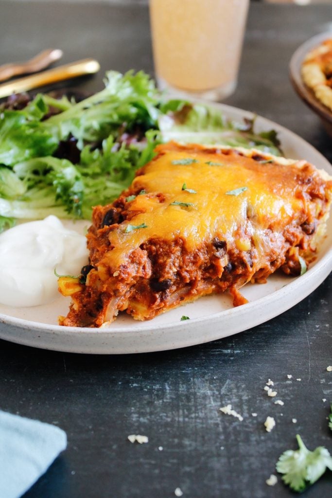 side view of tamale pie on a plate with a mixed green salad